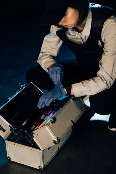 Cropped view of investigator in cap with investigation kit at crime scene — Stock Photo