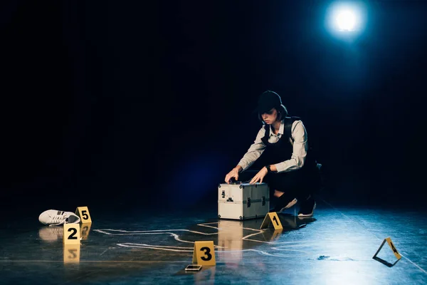 Investigator with investigation kit near chalk outline at crime scene — Stock Photo