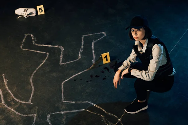 Overhead view of investigator near chalk outline and evidence markers at crime scene — Stock Photo