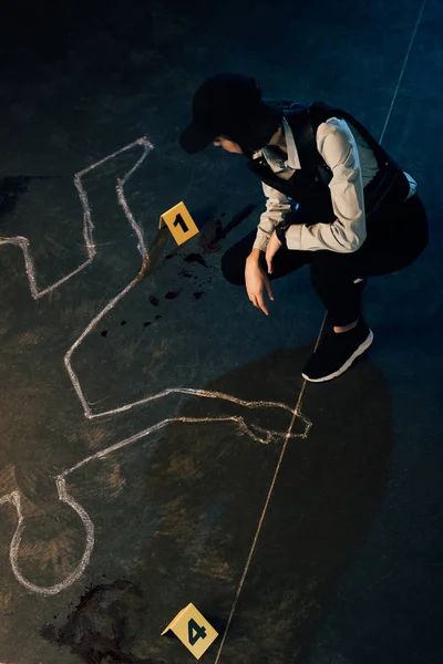 Vista aérea del investigador cerca del contorno de tiza y marcadores de evidencia en la escena del crimen - foto de stock