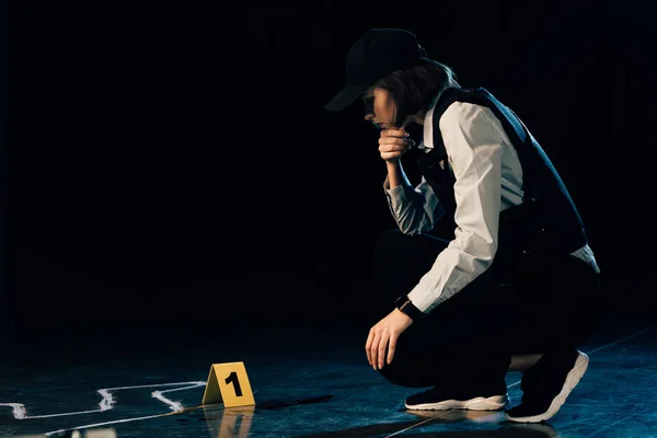 Investigator sitting near chalk outline at crime scene — Stock Photo