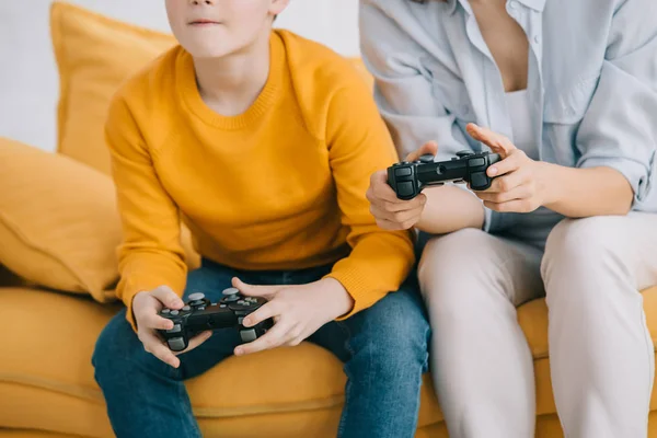 KYIV, UCRANIA - 8 de abril de 2019: Vista recortada de la madre y el hijo sosteniendo joysticks y jugando videojuegos - foto de stock