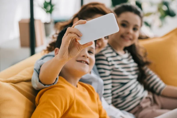 Selective focus of happy mother taking selfie with cheerful son and daughter — Stock Photo