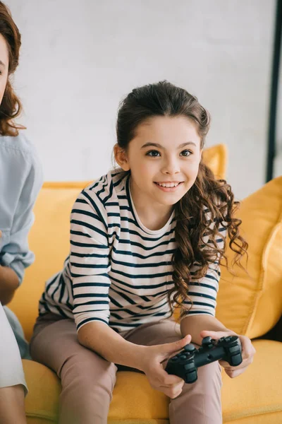 KYIV, UKRAINE - APRIL 8, 2019: Partial view of woman sitting near adorable child playing video game with joystick — Stock Photo