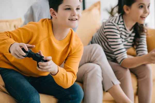 KYIV, UKRAINE - APRIL 8, 2019: Selective focus of cheerful boy playing video game together with sister — Stock Photo