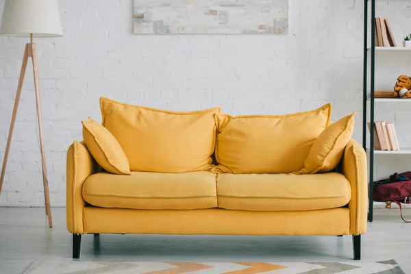 Spacious, light living room with bright yellow sofa, floor lamp and rack — Stock Photo