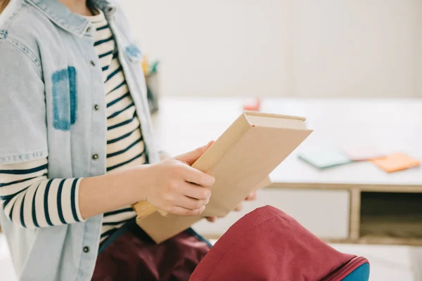 Ausgeschnittene Ansicht von Schulkind, das zu Hause Buch aus dem Rucksack holt — Stockfoto