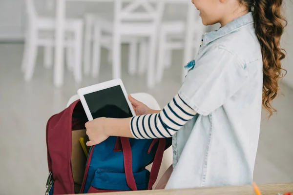 Vista parziale del bambino in età scolare che esce dal tablet digitale con schermo vuoto dallo zaino a casa — Foto stock