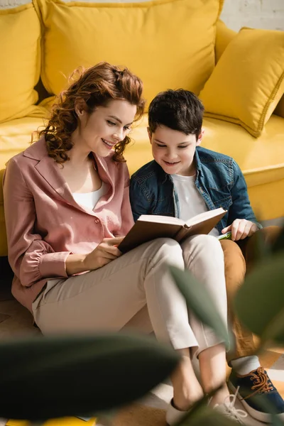Foyer sélectif de sourire mère et fils assis sur le sol et faire des devoirs ensemble — Photo de stock