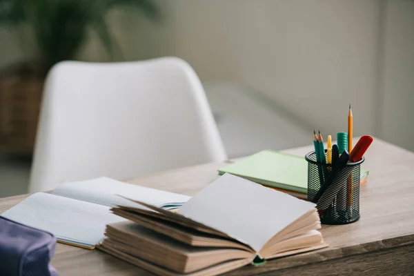 Messa a fuoco selettiva di scrivania in legno con libro aperto, libri di copia e cancelleria — Foto stock