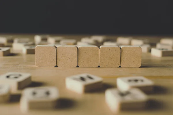 Enfoque selectivo de cinco cubos en blanco rodeados de bloques con letras en la superficie de madera aislada en negro - foto de stock