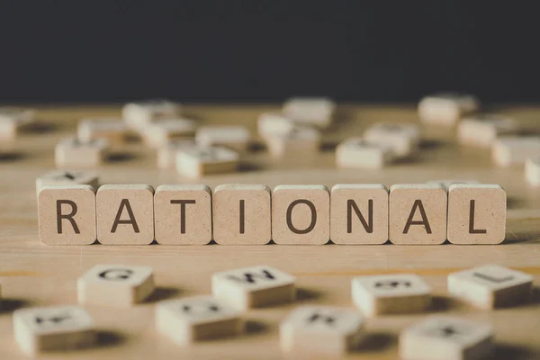Selective focus of rational inscription on cubes surrounded by blocks with letters on wooden surface isolated on black — Stock Photo