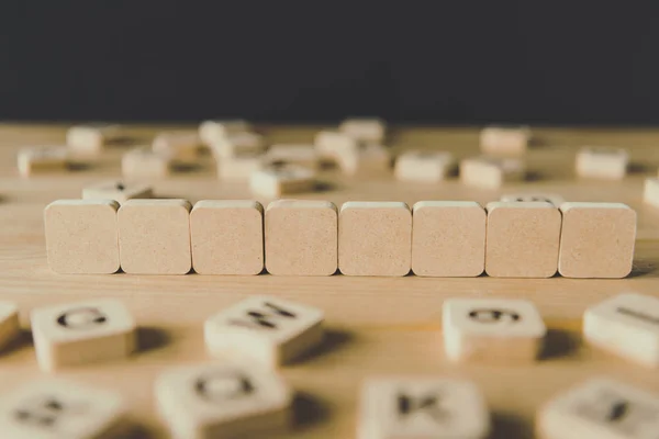 Enfoque selectivo de ocho cubos en blanco rodeados de bloques con letras en la superficie de madera aislada en negro - foto de stock