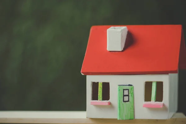 Modelo de casa con techo rojo y paredes blancas sobre fondo verde - foto de stock