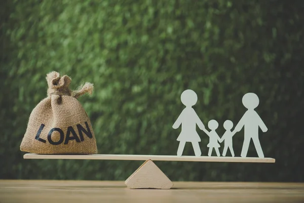 Bolsa de dinero con la inscripción del préstamo y el equilibrio de la familia de corte de papel en ver sierra sobre fondo verde - foto de stock