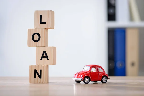 Wooden cubes with loan lettering and red toy car on wooden tabletop surface — Stock Photo