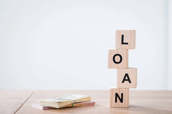 Dollar banknotes and wooden cubes with loan inscription on wooden surface isolated on grey — Stock Photo