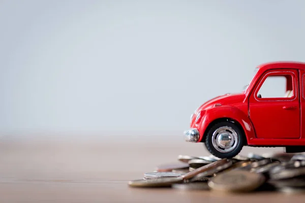 Red miniature car and metal coins on wooden surface isolated on grey — Stock Photo