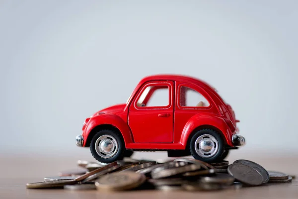 Red toy car on metal coins on wooden surface isolated on grey — Stock Photo