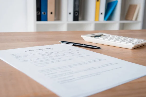 Contrat de prêt, stylo et calculatrice sur table en bois au bureau — Photo de stock