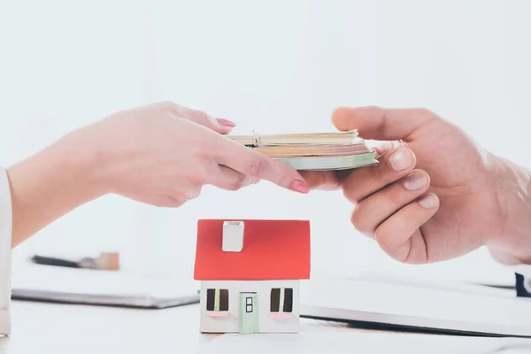 Vista parcial de gerente tomando dinero de la mujer cerca de modelo de casa - foto de stock