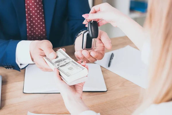 Cropped view of business man taking dollar banknotes from customer holding car keys — Stock Photo