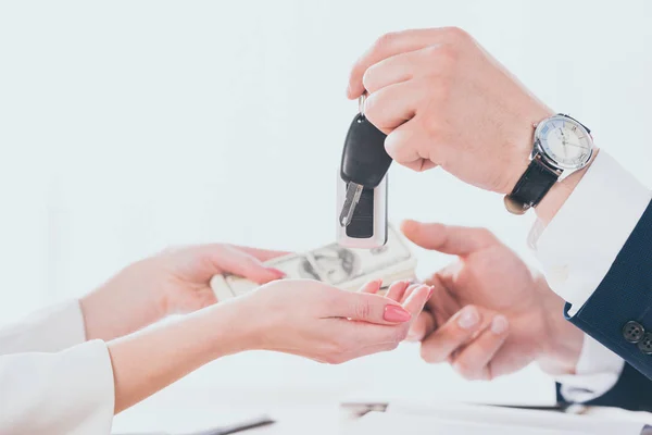 Vista recortada del hombre de negocios sosteniendo las llaves del coche y tomando el dinero del cliente - foto de stock