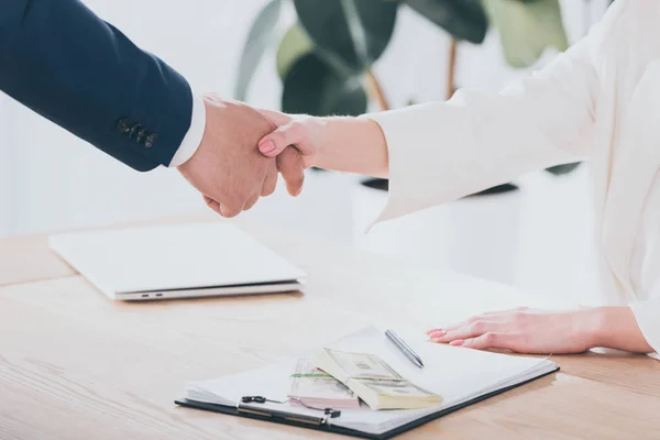 Recortado disparo de hombre de negocios estrechando la mano con el cliente en la oficina - foto de stock