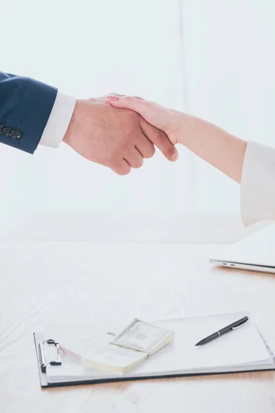 Partial view of businessman and woman shaking hands in office — Stock Photo