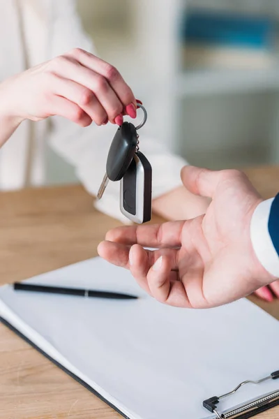 Vue partielle de la femme prenant des clés de voiture de l'homme d'affaires au bureau — Photo de stock