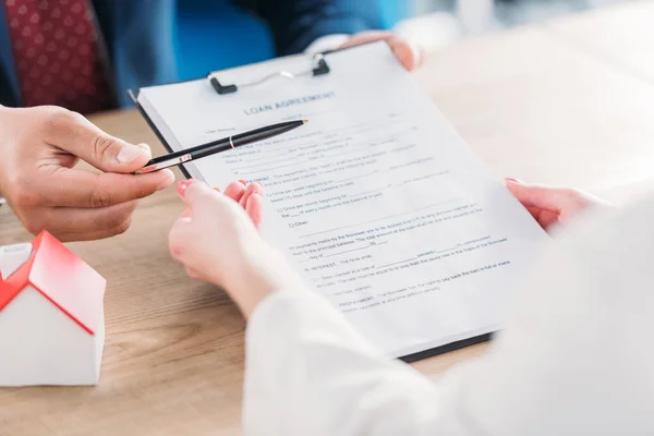 Teilansicht des Geschäftsmannes, der dem Kunden Stift und Klemmbrett mit Darlehensvertrag gibt — Stockfoto