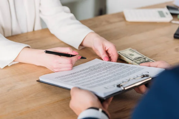 Vue recadrée de femme signature contrat sur presse-papiers dans les mains de l'homme d'affaires — Photo de stock