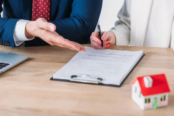 Vue partielle de l'homme d'affaires montrant la place de signature dans le contrat de prêt au client tenant stylo — Photo de stock