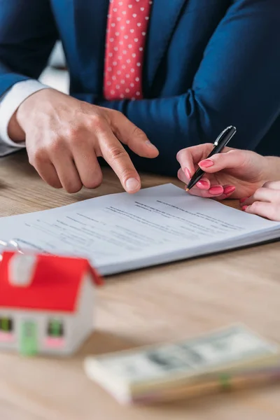 Vue partielle de l'homme d'affaires pointant à la place de signature dans l'accord de prêt près du client tenant stylo — Photo de stock