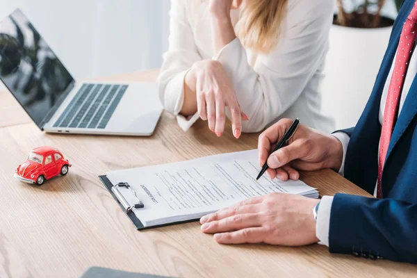 Plan recadré de l'homme signature d'un accord de prêt près de concessionnaire de voiture au bureau — Photo de stock