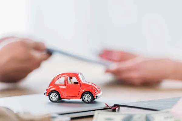 Visão parcial do empresário e cliente perto de carro de brinquedo vermelho no escritório — Fotografia de Stock