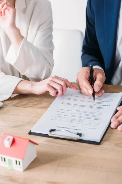 Geschnittene Ansicht von Mann unterschreibt Darlehensvertrag in der Nähe Geschäftsfrau zeigt auf Ort der Unterschrift — Stockfoto