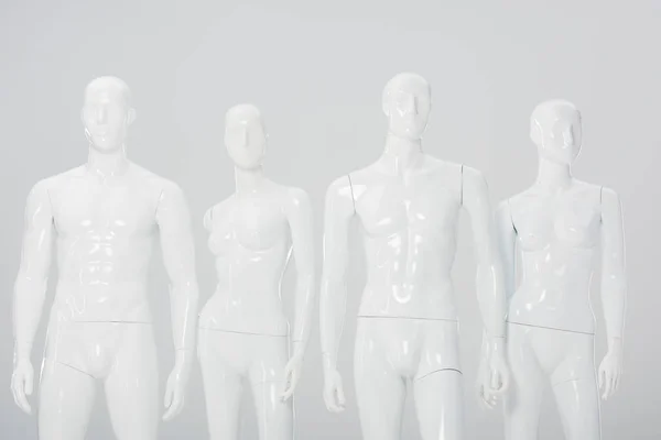 Белые пластиковые манекены в ряд изолированы на сером — стоковое фото