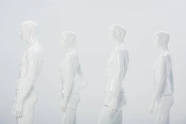 White plastic dummies in row isolated on grey — Stock Photo