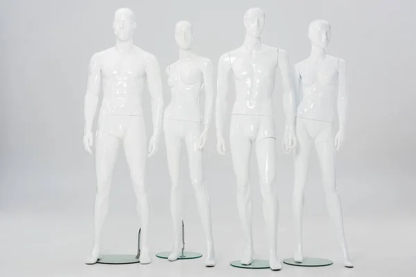 Білі пластикові манекени в ряд на сірому — стокове фото