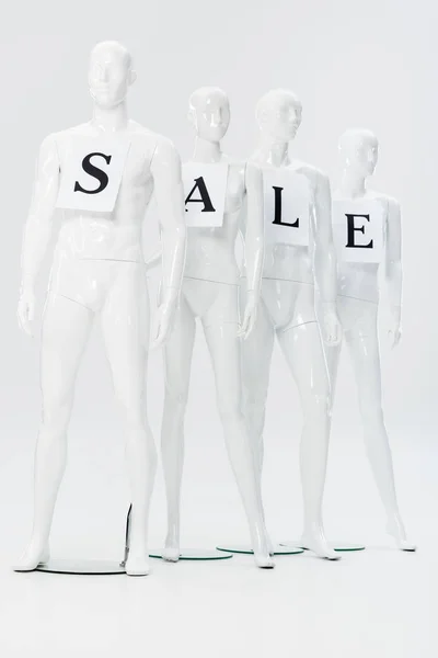 Papiers avec lettrage de vente sur mannequins en plastique blanc sur gris — Photo de stock