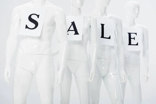 Papiers avec lettrage de vente sur mannequins en plastique blanc sur gris — Photo de stock