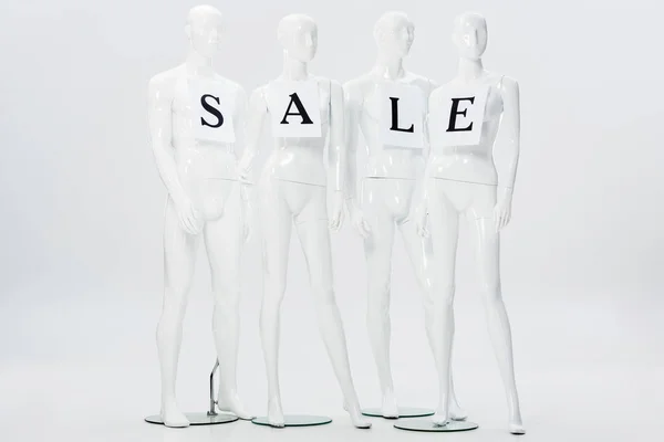 Papiers avec lettrage de vente sur mannequins blancs isolés sur gris — Photo de stock