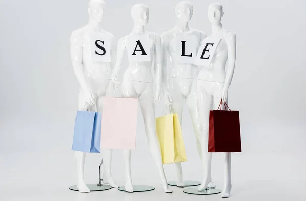 Белый манекены с надписью продажи на бумагах и торговых мешках изолированы на сером — стоковое фото
