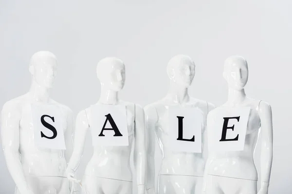 Papers with sale lettering on white mannequins isolated on grey — Stock Photo