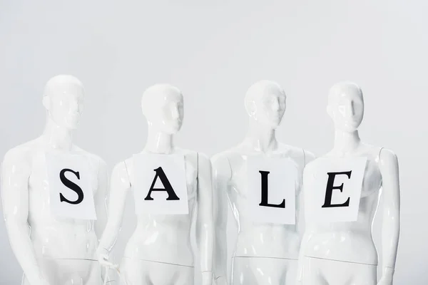 Papeles con letras de venta en maniquíes blancos aislados en gris - foto de stock