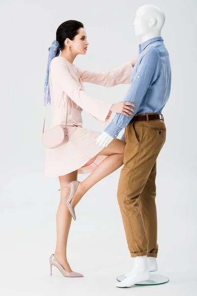 Beautiful girl in dress hitting mannequin on grey — Stock Photo