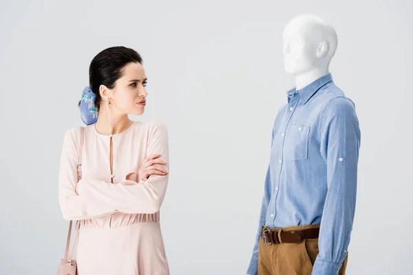 Beautiful dissatisfied girl with crossed arms looking at mannequin isolated on grey — Stock Photo
