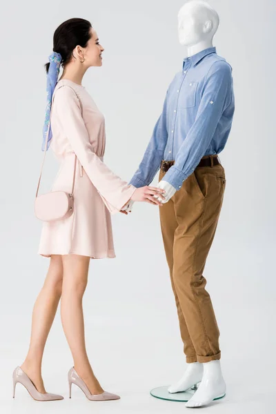 Beautiful girl holding hands with mannequin isolated on grey — Stock Photo