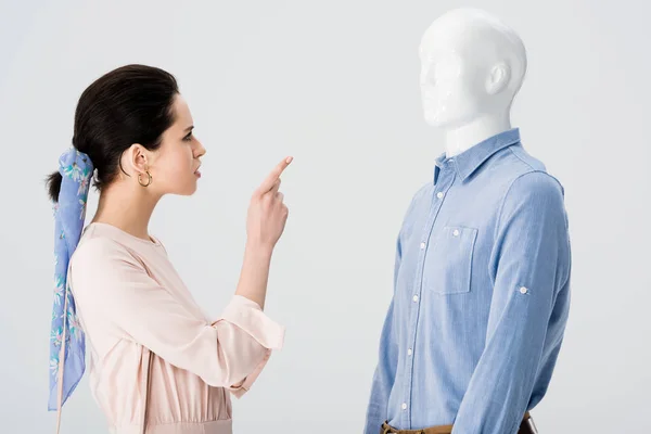 Незадоволена дівчина сперечається і вказує пальцем на манекен ізольовано на сірому — стокове фото